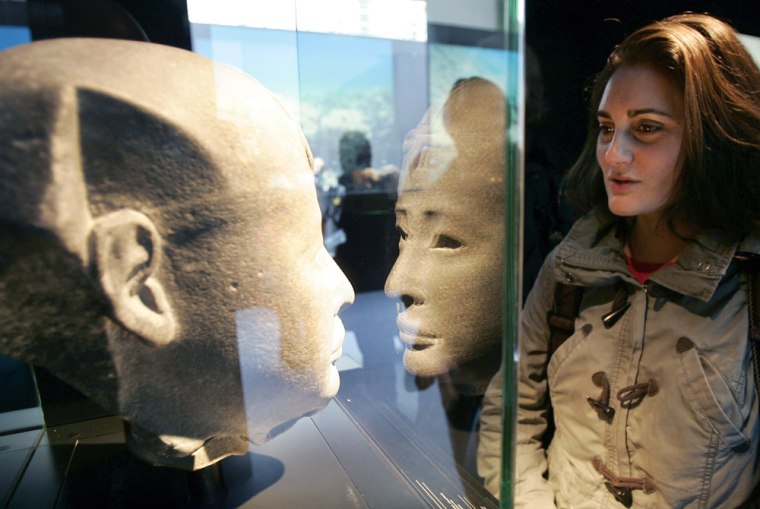 A visitor to the "Egypt's Sunken Treasures" exhibit at Paris' Grand Palais looks at a pharaoh's head made of diorite stone. 