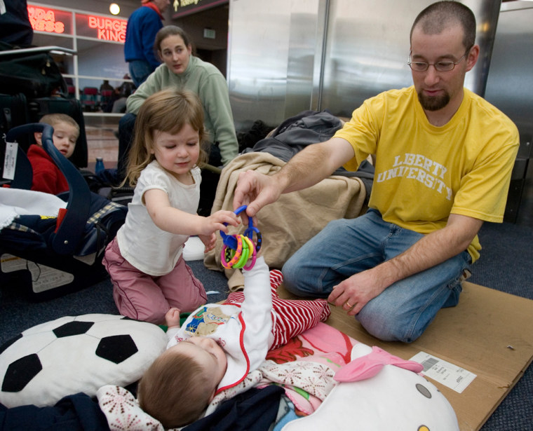 Andy Hartfield plays with his five-month-old son, Micah, and daughter, Alexis, 3, while waiting for flight information at Denver International Airport on Thursday.