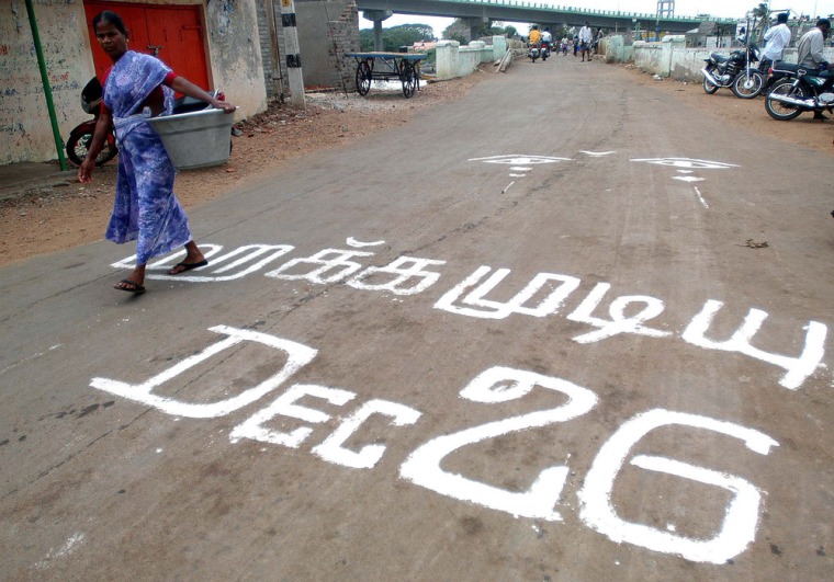 A woman walks past writing on a road marking the second anniversary of the Dec. 26, 2004, Asian tsunami in Keechankuppam, India. The writing says, "We cannot forget the day."