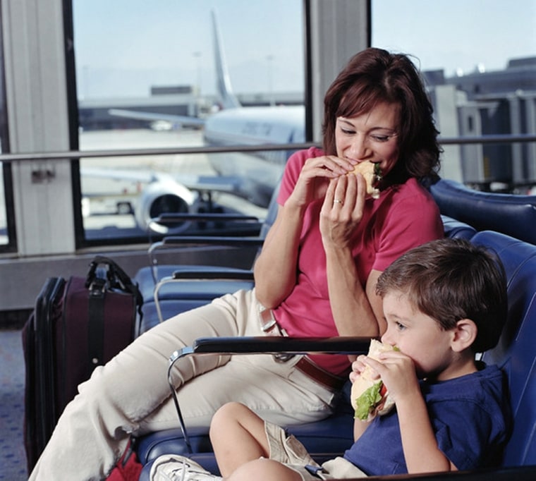 Mother and son (2-4) eating sandwiches in airport waiting area