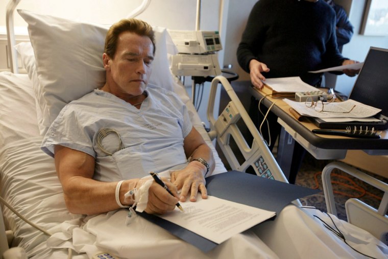In this photo provided by his press office, California Gov. Arnold Schwarzenegger signs an order creating the Public Employee Post-Employment Benefits Commission in his hospital room in Santa Monica, Calif., on Dec. 28.