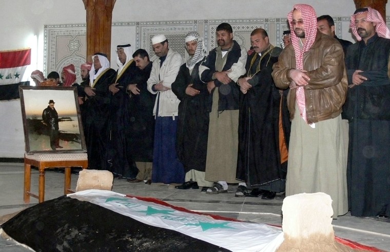 Men pray over the coffin of Iraq's former president Saddam Hussein during a funeral in Awja