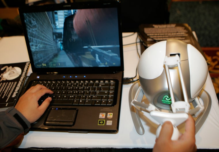 Show attendee plays a PC game with Novint's Falcon controller, right, during the media preview at the Consumer Electronics Show in Las Vegas. The controller allows users to feel 3D motion and force effects when playing games.