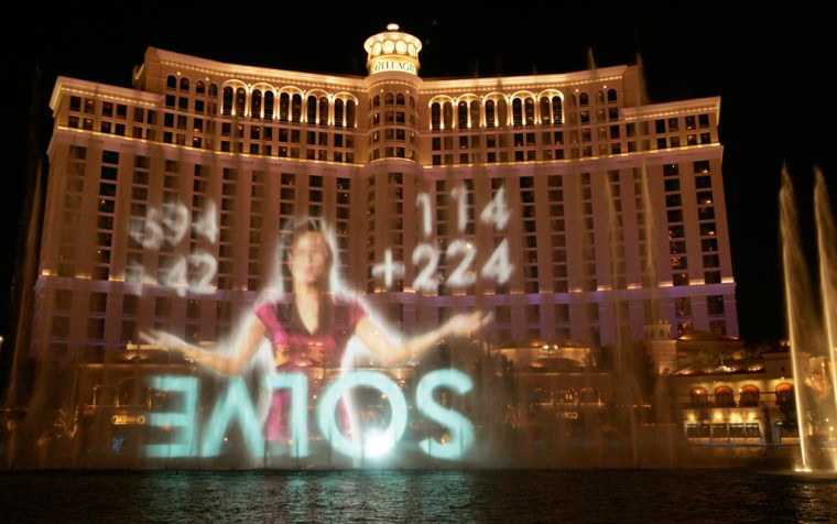 A video of a woman announcing the online puzzle game \"Vanishing Point\" is projected onto a water fountain in front of the Bellagio hotel in Las Vegas