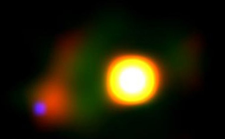 A color image of the Mira system constructed from an archival Hubble Space Telescope image. Mira B glows blue because of the violent shock front formed as the inner part of the disk crashes into the central star. The dust outflow from Mira A has a green color. The more red color from Mira B comes from the opaque edge of the disk being heated by Mira A.