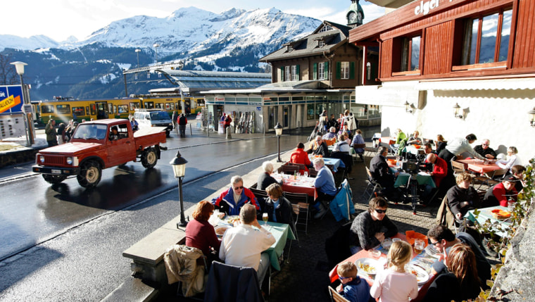 People in sunny thaw sit at the tables of a restaurant in Wengen, Switzerland, on Wednesday, Jan. 10, 2007. A men's World Cup downhill ski training session was canceled in Wengen on Wednesday to preserve the Lauberhorn course, which has been damaged by rain and warm weather. (AP Photo/Keystone, Alessandro Della Bella)