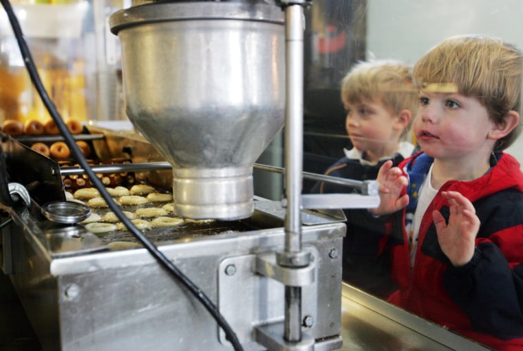 Anderson LeGrand, right, and Wilson Brown watch mini-doughnuts being fried at Mighty-O Donuts in Seattle. The company produces all-natural, organic, vegan doughnuts.