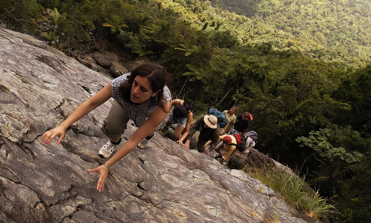 Ellie Botshon, of New York, climbs a rock at the south side of the Caribbean National Rain Forest, commonly called El Yunque. Puerto Rico has been aggressively branding itself a no-passport destination for Americans.