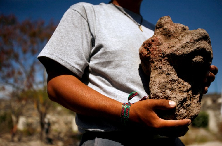 Archeologist Victor Manuel Castro Mendoza holds up a stone believed to be a statue of an animal representation at the recently discovered Zazacatla archeological site near the town of Xochitepec, Mexico, Jan. 25, 2007. The site is a 2,500-year-old city influenced by the Olmecs,  hundreds of miles away from the Olmecs' Gulf coast territory, archaeologists said.(AP Photo/Dario Lopez-Mills)