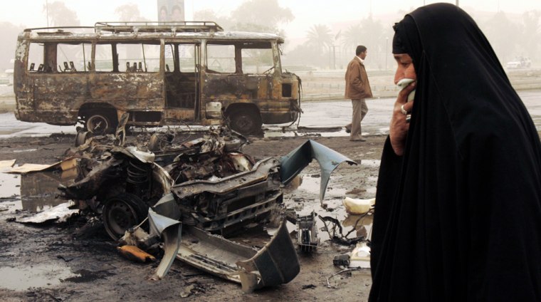 A woman walks past the scene of a bomb attack in Baghdad