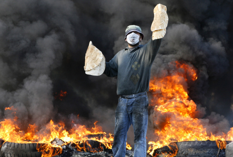A Lebanese protester holds up bread as he stands in front of burning tires in the southern city of Sidon on Jan. 23. Hezbollah-led opposition protesters seek to topple U.S.-backed Prime Minister Fuad Saniora. 