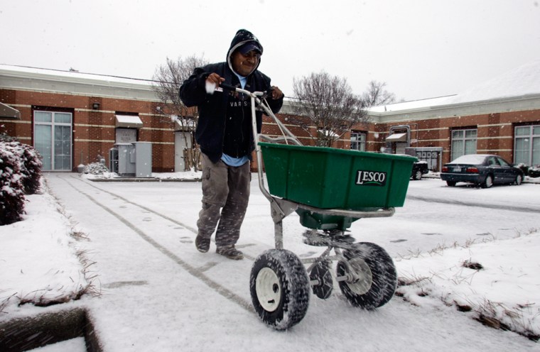 Alfredo Fuentes spreads salt on a sidewalk in Charlotte, N.C., on Thursday. forecasters warned that snow and eventually freezing rain could knock out power and make roads treacherous.