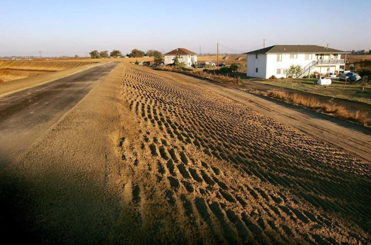 A levee is being constructed to protect a future housing development, left, but does not protect long-time residents' homes, right, on Bethel Island, one of the residential islands surrounded by levees that hold back the higher waters of the Sacramento-San Joaquin River Delta, west of Stockton, California, on Sept. 29, 2005. 
