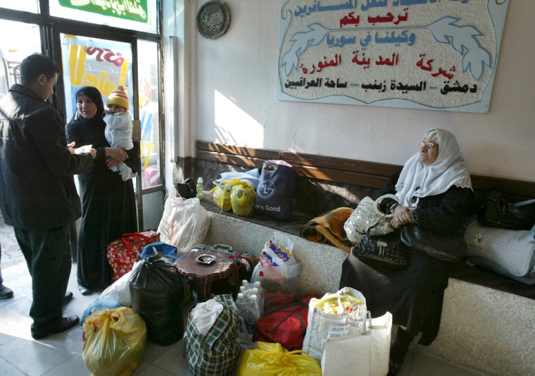 Travellers wait with their luggage at a travel agent in Baghdad