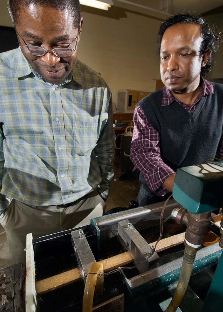 Forestry professor Laurent Matuana, left, and post-doctoral assistant Omar Faruk, right, keep an eye on a composite lumber being extruded at the Natural Resources Building on the campus of Michigan State University, Friday Feb. 2, 2007, in East Lansing, Mich. The lumber being produced is wood based, however, the same process can also produce manure based lumber.  (AP Photo/Kevin W. Fowler)