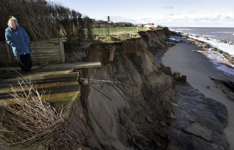 Diana Wrightson, the owner of Cliff House, which is now only about 15 feet (five meters) from the edge of the cliff, which once held a garage, several bungalows and a small road behind the guest house, pauses next to the destruction due to errosion caused by rising seal level, at the northeastern coastal village of Happisburgh, in Norfolk, England, Wednesday Jan. 24, 2007.  Since 1990, nearly 25 bungalows have been lost because of falling cliffs in and around Happisburgh, a village of Edwardian homes. It's a long-standing problem in the region, unrelated to global warming, but Britain's government has decided in its new plan for flood and coastal defenses that this area isn't worth defending by replacing its nearly 50-year-old offshore timber barrier that has broken apart. \"The next big storm could take us away,\" she said. (AP Photo/Lefteris Pitarakis)