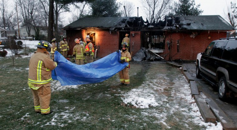 Firefighters roll up a blue tarp in front of a home fire that killed 10 people, six of them children, in Bardstown, Ky., on Feb. 6.