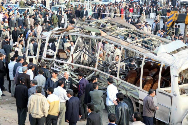 People gather around the remains of a bus following an explosion targeting Iran's elite Revolutionary Guards, in the southeastern city of Zahedan on Wednesday.