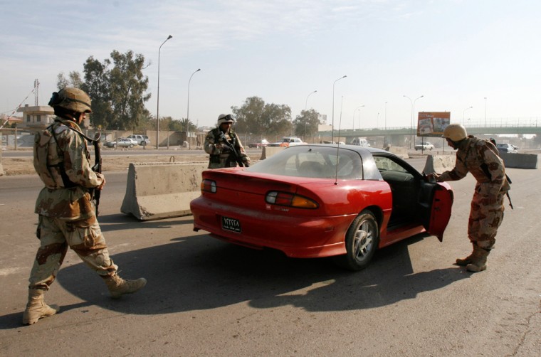 Iraqi soldiers stop a  vehicle at a checkpoint in Baghdad