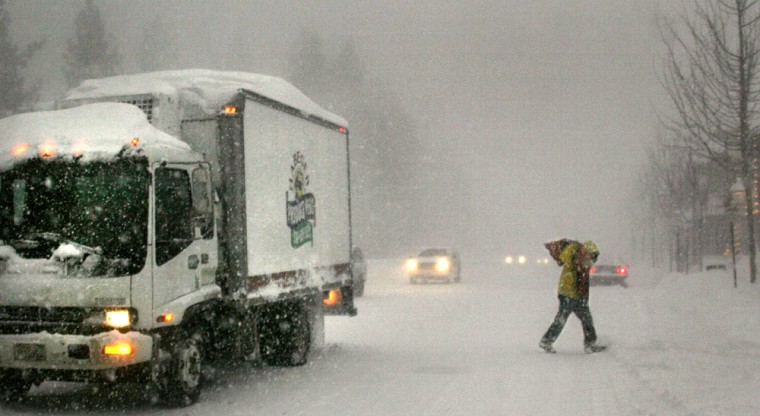 A truck driver delivering produce runs across California Highway 28 in Tahoe City, Calif., on Monday as the stongest winter storm of the season dumped several feet of snow in the Lake Tahoe and Sierra Nevada area.