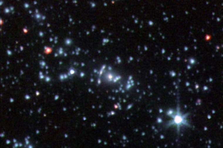 This infrared image, taken by NASA's Spitzer Space Telescope, shows a part of the galaxy cluster Abell 2667. The "Comet Galaxy" is the bright red object seen to the left of the cluster center. Credit: NASA, Spitzer Space Telescope 