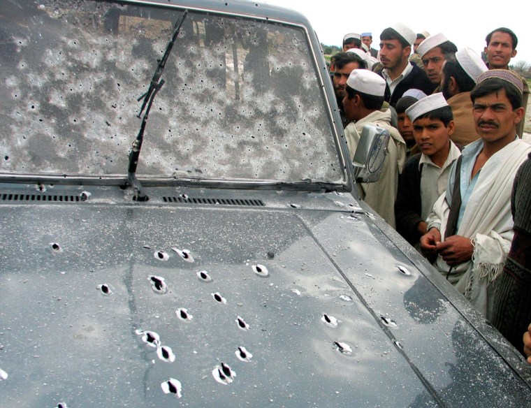 Afghans look at a car, damaged by bullets after an incident involving foreign troops, in Spin Pul village in the eastern province of Ningarhar