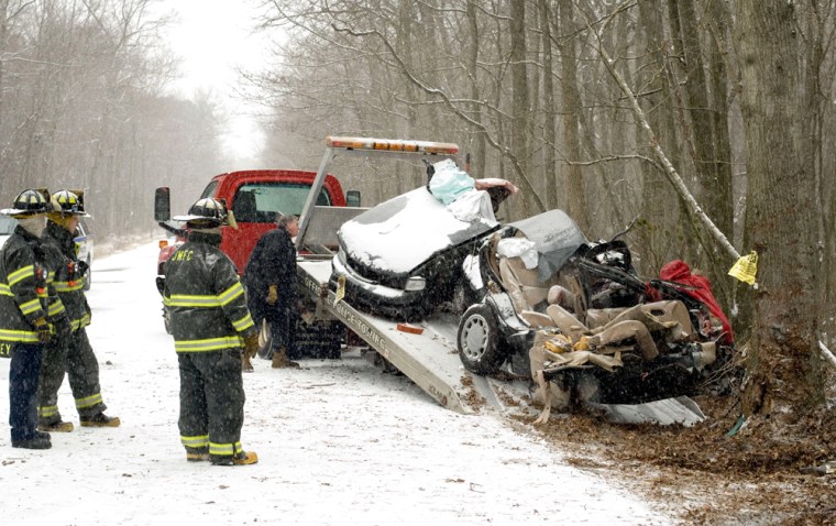 Firefighters look on as the second half of a car involved in a fatal accident is loaded onto a tow truck Wednesday in Jackson, N.J. A brother and sister died in the accident.