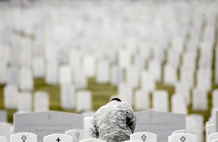 A soldier kneels at a grave at Arlington National Cemetery in Arlington, Va. this past Wednesday. As of 10 a.m. on Friday, 3,197 military deaths were reported by the Pentagon.