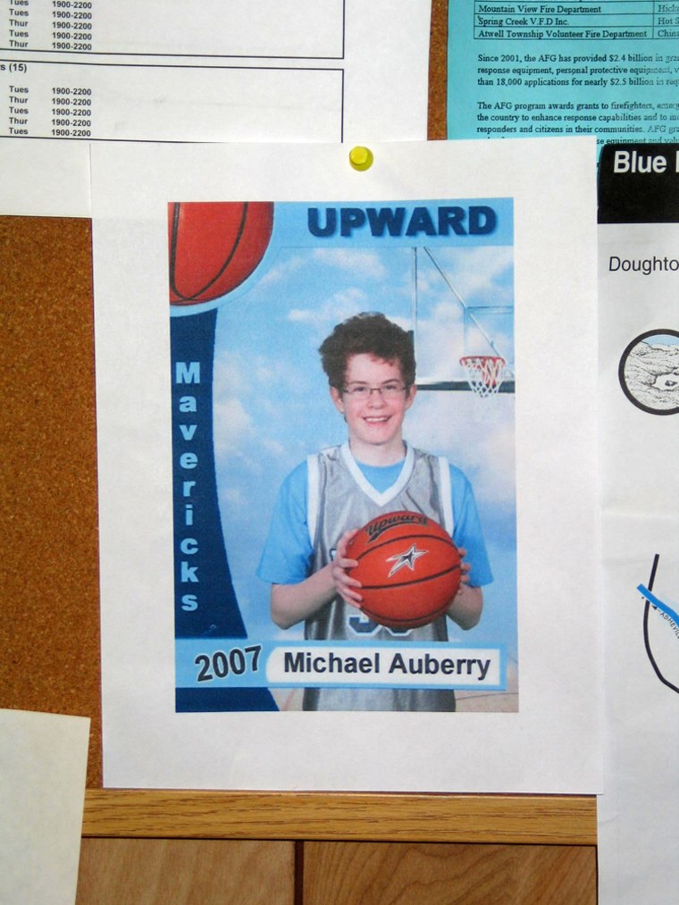 Search teams are combing mountain terrain for Michael Auberry, shown in a poster at the volunteer fire department in McGrady, N.C.