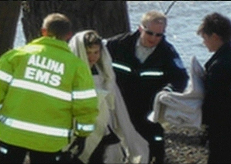 Rescuers wrap Amos Benjamin Cohen in blankets after he was brought to shore after his unexpected river ride.