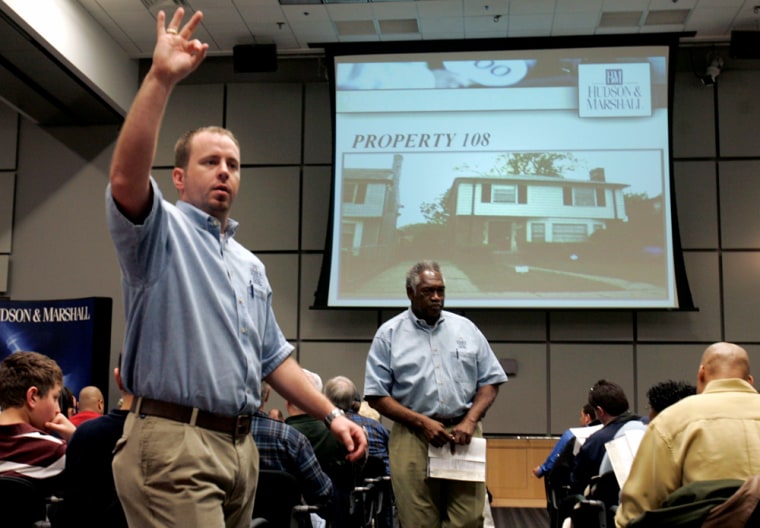 Auction worker Pace signals a bid on property 108 for a bidder during an auction in Dearborn