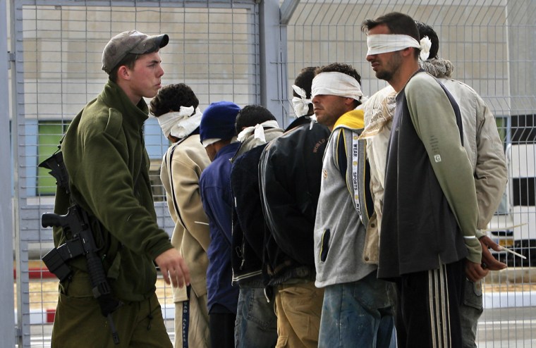 An Israeli soldier guards Palestinian workers caught working illegally in Israel as they are lined up and blindfolded at the Erez Crossing on March 1, before being returned to the Gaza Strip.