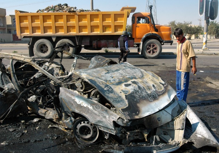 A man stands near wreckage left by a car bomb blast in the southwestern Baghdad neighborhood of Bayaa on Thursday.