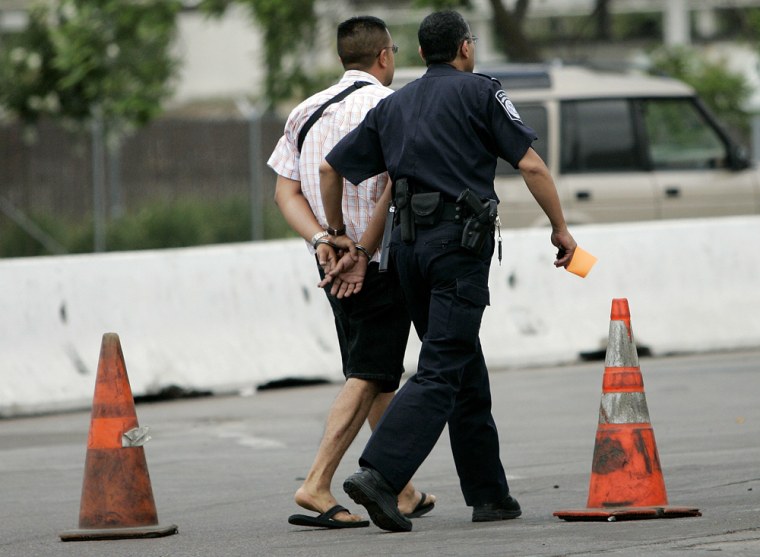 A Customs and Border Protection officer escorts a motorist who was arrested at the Otay Mesa Port of Entry on July 28, 2006, in Otay Mesa, Calif., at the border with Mexico.