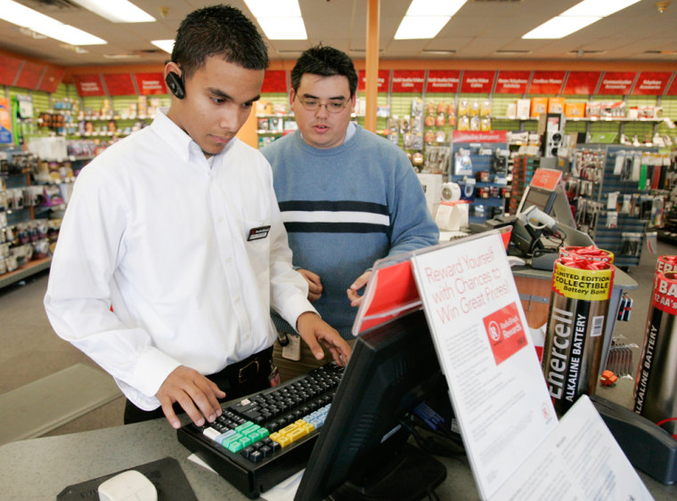 RadioShack sales associate Carlos Penate, left, is walked through a sale by store manager Ryan Yamamoto, right, at a store location in Carrollton, Texas. America’s employers ramped up hiring in March, adding a surprisingly strong 180,000 jobs.