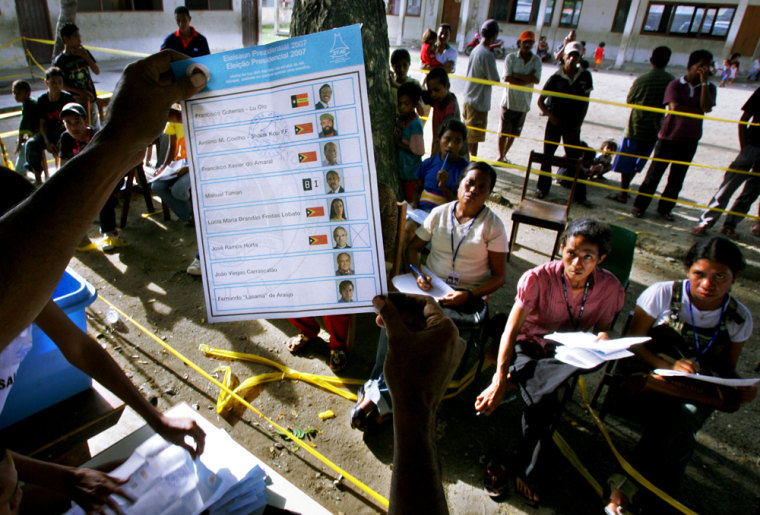 An election official holds up a ballot Monday as witnesses look on at a polling station in Dili.