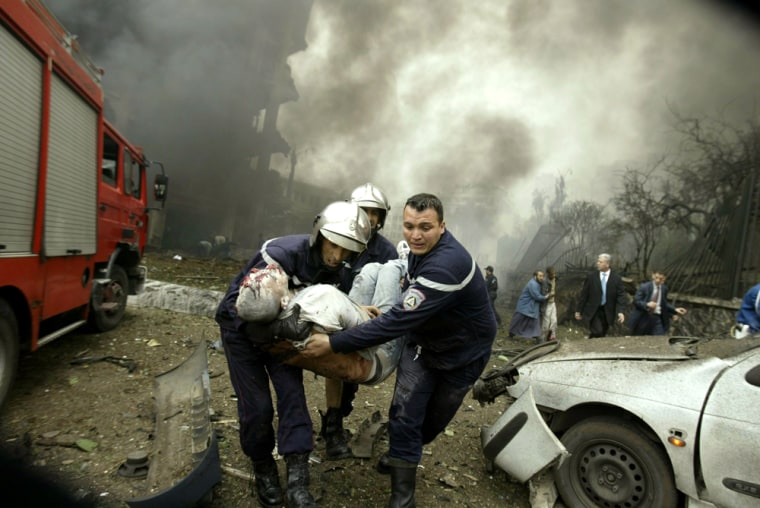 Firemen evacuate a victim of a suicide car bomb near the prime minister's headquarters in central Algiers
