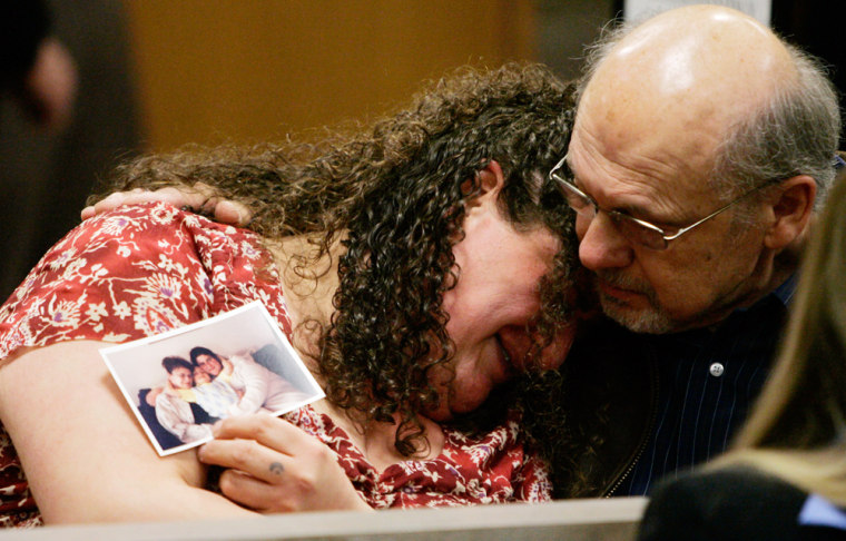 Charlene Kafoury, holding a photo of herself with her mother, is consoled by an unidentified person  in a courtroom as Anthony LaCalamita III, not shown,  the man accused of killing  Kafoury's mother, is arraigned on murder and other charges in District Court in Troy, Mich., Wednesday, April 11, 2007. LaCalamita, a recently fired accountant, is accused of killing a former co-worker and wounding two others during a shotgun attack at the office building in which he previously worked. (AP Photo/Carlos Osorio)