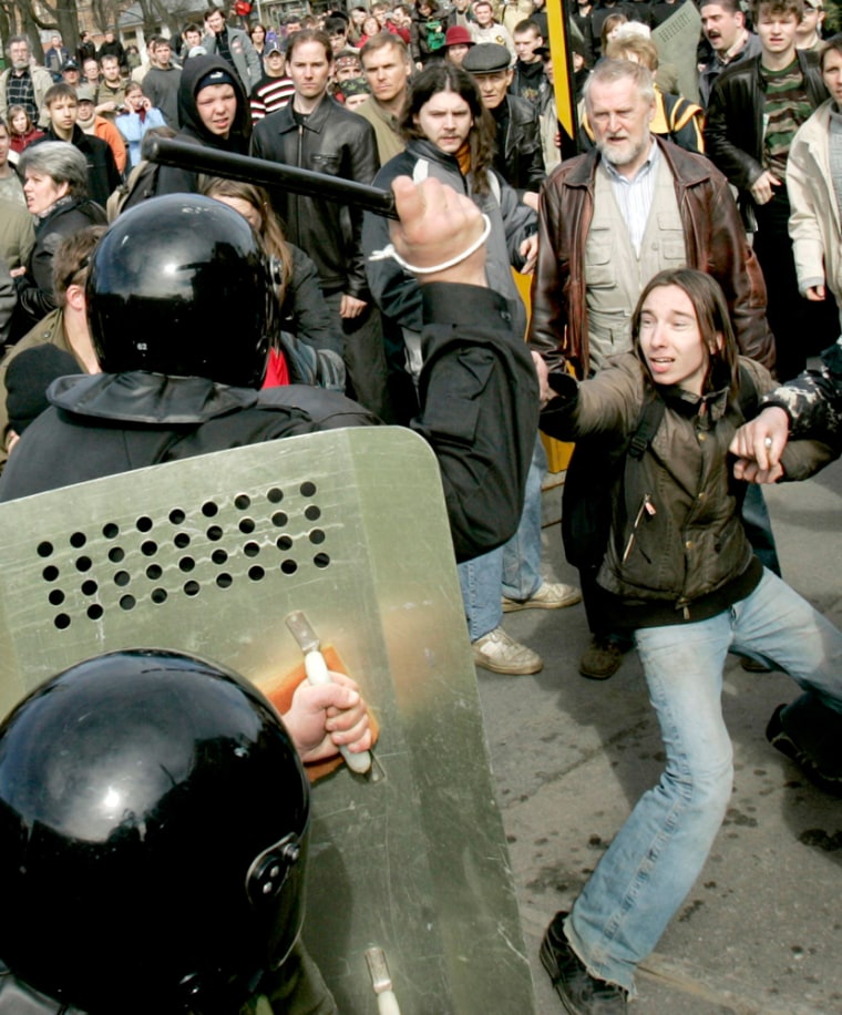 A riot police officer threatens a demonstrator with a baton during a protest in St Petersburg