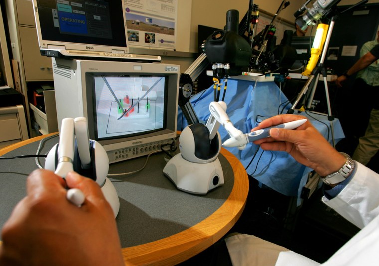 Dr. Mika Sinanan's hands can be seen at the controls in a demonstration of a robotic surgeon nicknamed Raven (right background), at the University of Washington's Electrical Engineering Building in Seattle. Raven will participate in NASA's mission to submerge a surgeon and robotic gear in a simulated spaceship.