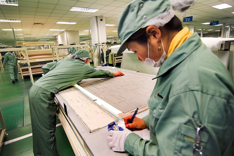 Workers handle solar cells to produce solar panels in the factory run by Suntech Power in Wuxi, China.