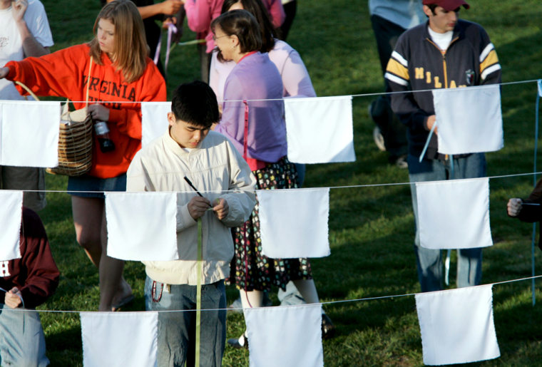 Students gather around white prayer flags outside West Ambler Johnston Hall on the Virginia Tech campus Monday.