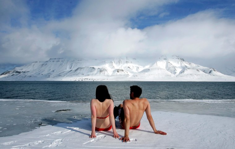 Climate activists Lesley Butler and Rob Bell \"sunbathe\" on the edge of a frozen fjord in the Norwegian Arctic town of Longyearbyen