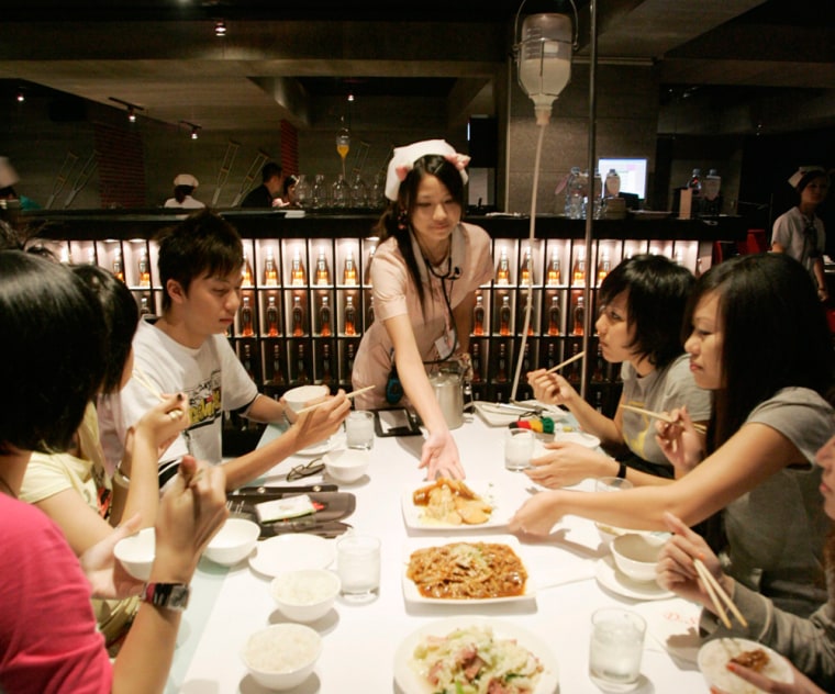 A waitress dressed as a nurse serves food to customers at a hospital style restaurant in Taipei