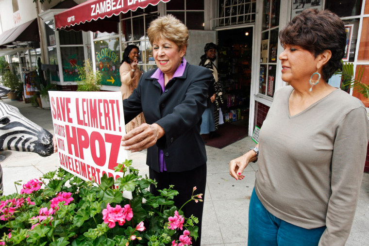 ** ADVANCE WEEKEND APRIL 28-29 ** Jackie Ryan, left, and sister Mary Kimbrough,co-owners of Zambezi Bazaar, adjust a sign in front of their store in Leimert Park Village section of Los Angeles, April, 6, 2007. The sisters believe the city is trying to replace black businesses in Leimert with those catering to wealthier white customers to boost tax revenues. Since 1991, their store has sold everything from old copies of Negro Digest, the predecessor to Ebony magazine, to earrings and statues from Africa. (AP Photo/Kevork Djansezian)