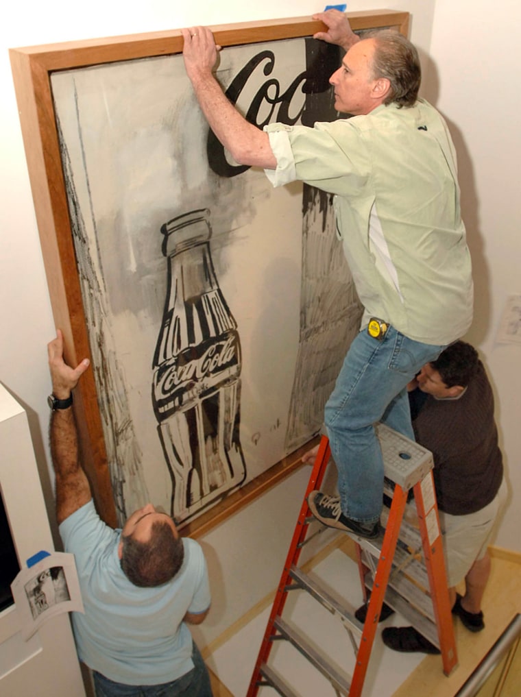 Workers hand one of Andy Warhol's paintings in the World of Coca-Cola museum on Wednesday.