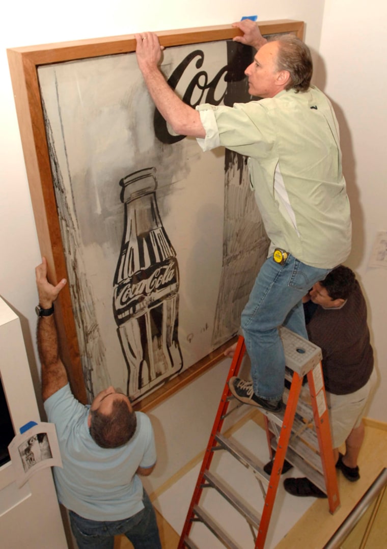 Workers hang one of Andy Warhol's works on May 2, in the new World of Coca-Cola museum in Atlanta. About 30 of the paintings, pencil sketches, and screenprints will be on view at the museum. 