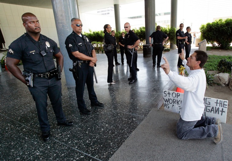 An unidentified immigrant-rights activist demonstrates Tuesday in front of Los Angeles police officers outside police headquarters in Los Angeles. 
