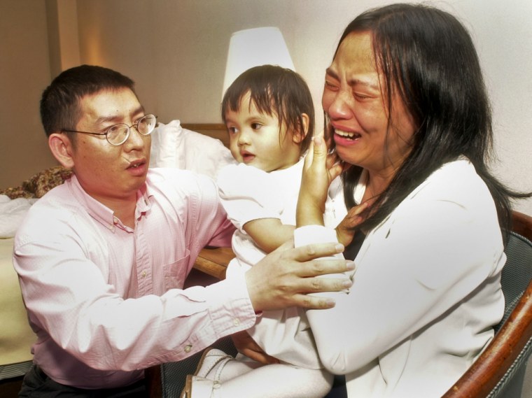 Shaoqiang He, left, comforts his wife, Qin Luo He, as she holds their younger daughter, Avita, in their hotel room in Memphis, Tenn., in May 2004. They are battling with foster parents for custody of their older biological daughter.
