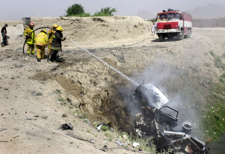 Afghan firefighters douse the smoldering wreckage of a truck destroyed by a remote-controlled bomb in Kandahar, Afghanistan, on Thursday.